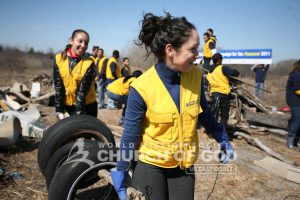 Two World Mission Society Church of God volunteers moving old tires at Breezy Point Beach cleanup
