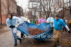 ASEZ volunteers from the World Mission Society Church of God holding a tarp of fallen branches during Mothers Street cleanup in Newburgh NY