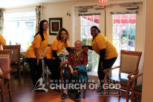 World Mission Society Church of God volunteers posing with resident of Laurel Place Assisted Living during senior center visit