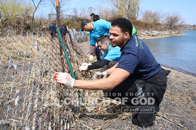 Volunteers worked meticulously to remove debris from a fence during the Clason Point Park Cleanup.