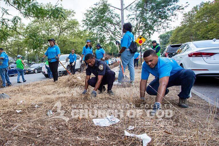 ASEZ volunteers and NYPD officer removing weeds from roadside