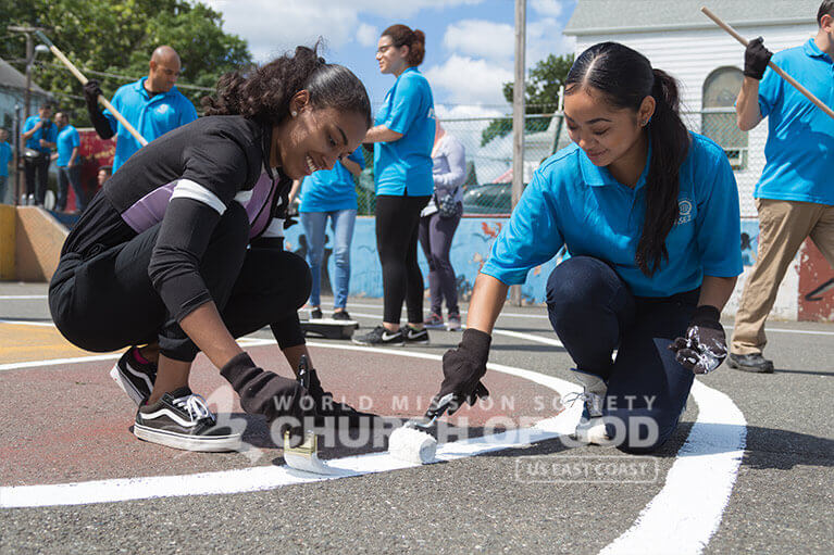 ASEZ student volunteers repainting the lines of a basketball court in Wrigley Park.